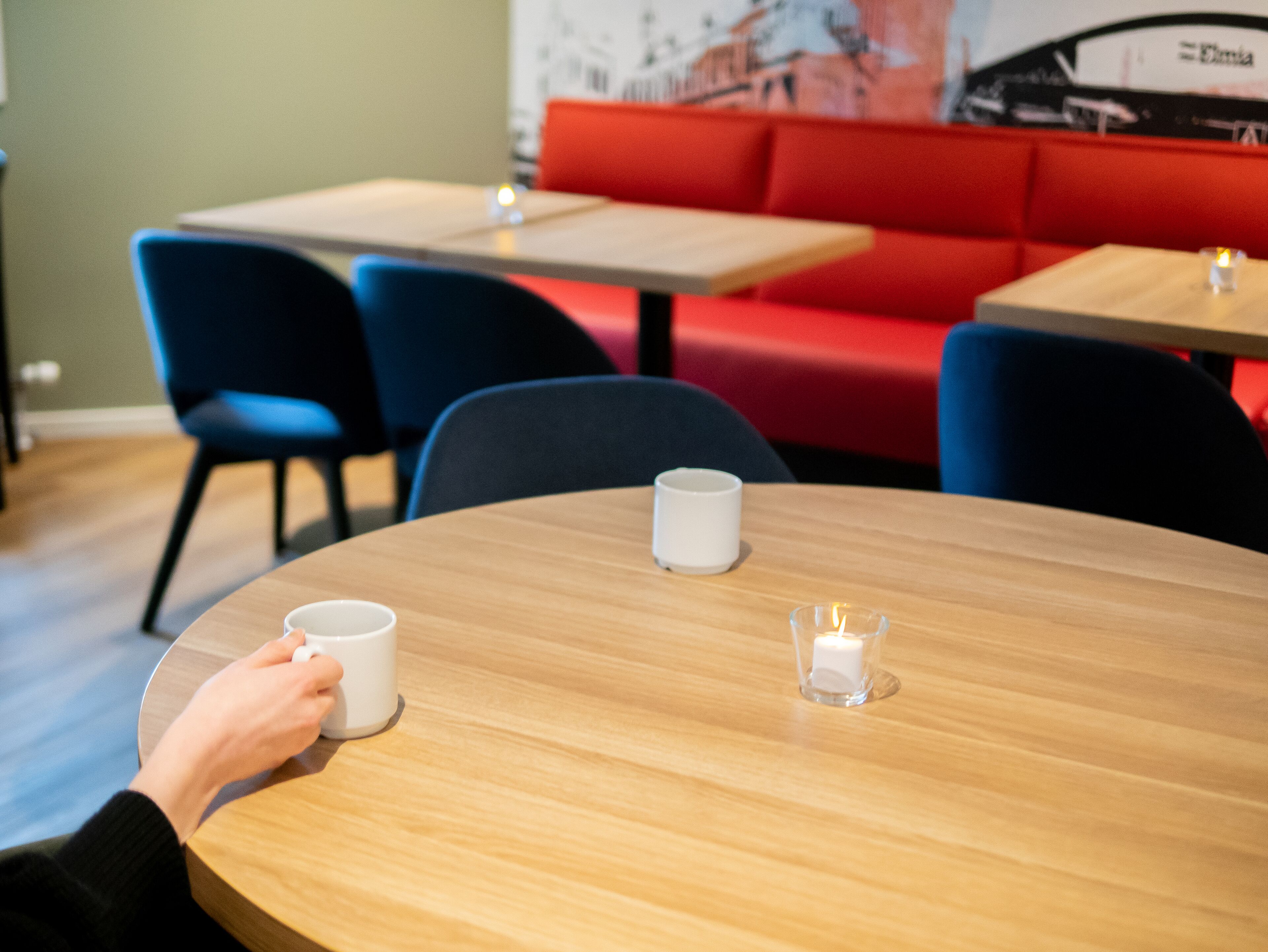 A round wooden table with a white mug and a candle.