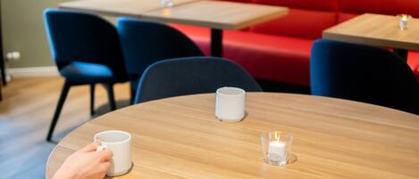 Una mesa redonda de madera con una taza blanca y una vela.