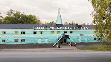 Un edificio con el letrero "GOOD MORNING HOTELS" y un llamativo esquema de color verde y azul.