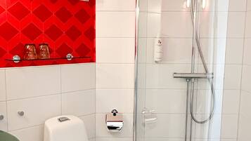 A modern bathroom with a glass-enclosed shower, a white toilet, and a red patterned wall.