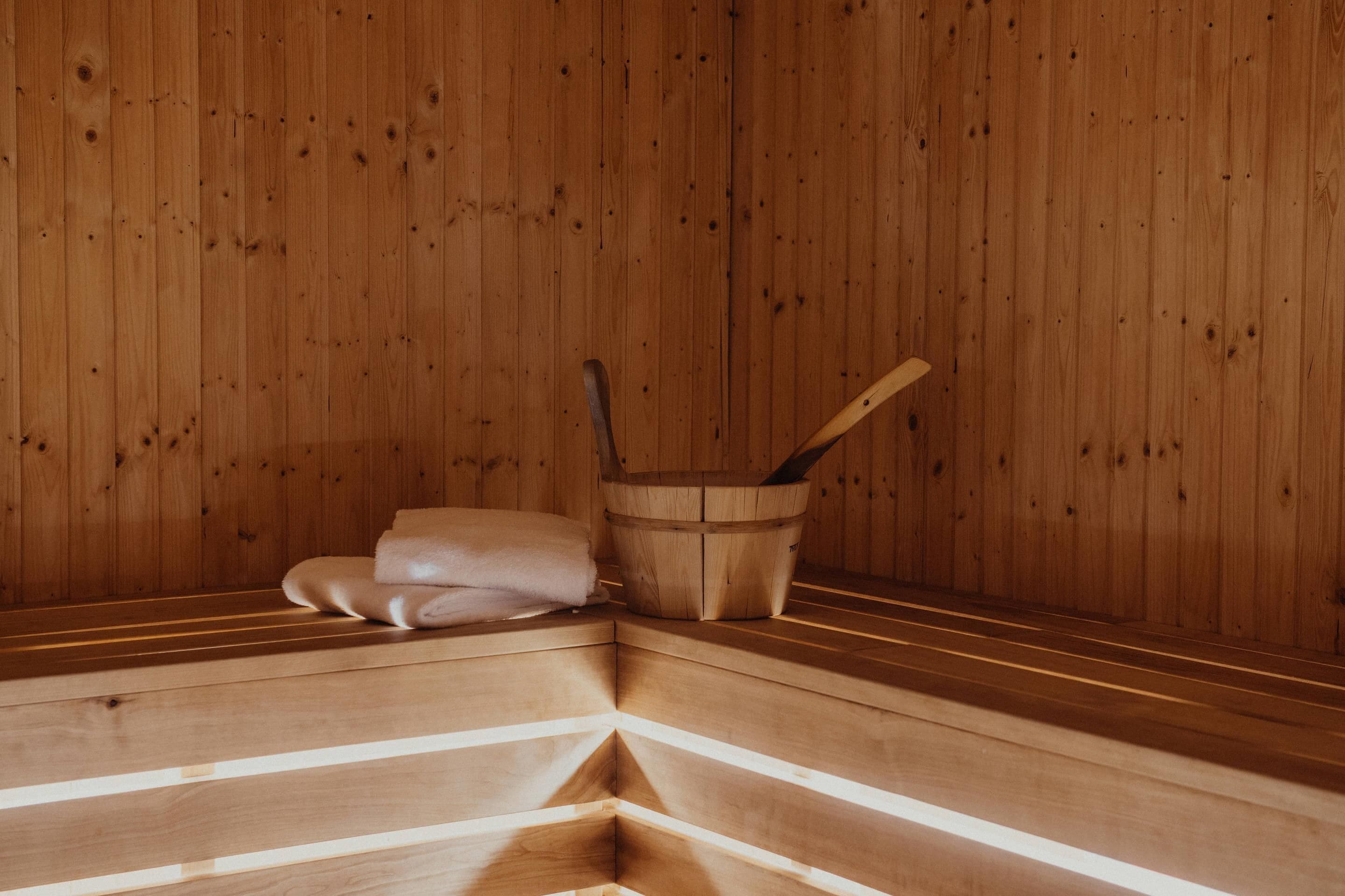 Eine Holzsauna mit Bänken und einem Holzeimer.