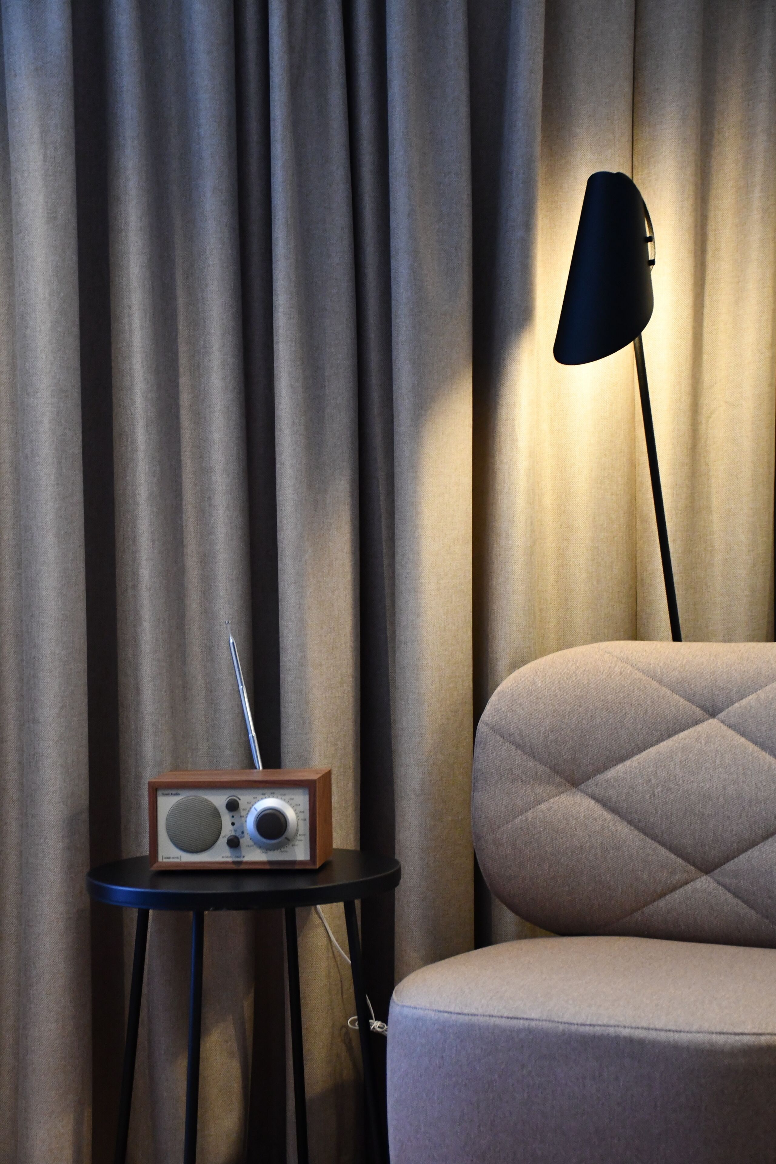 A room with a chair, a small table with a radio, and a lamp.
