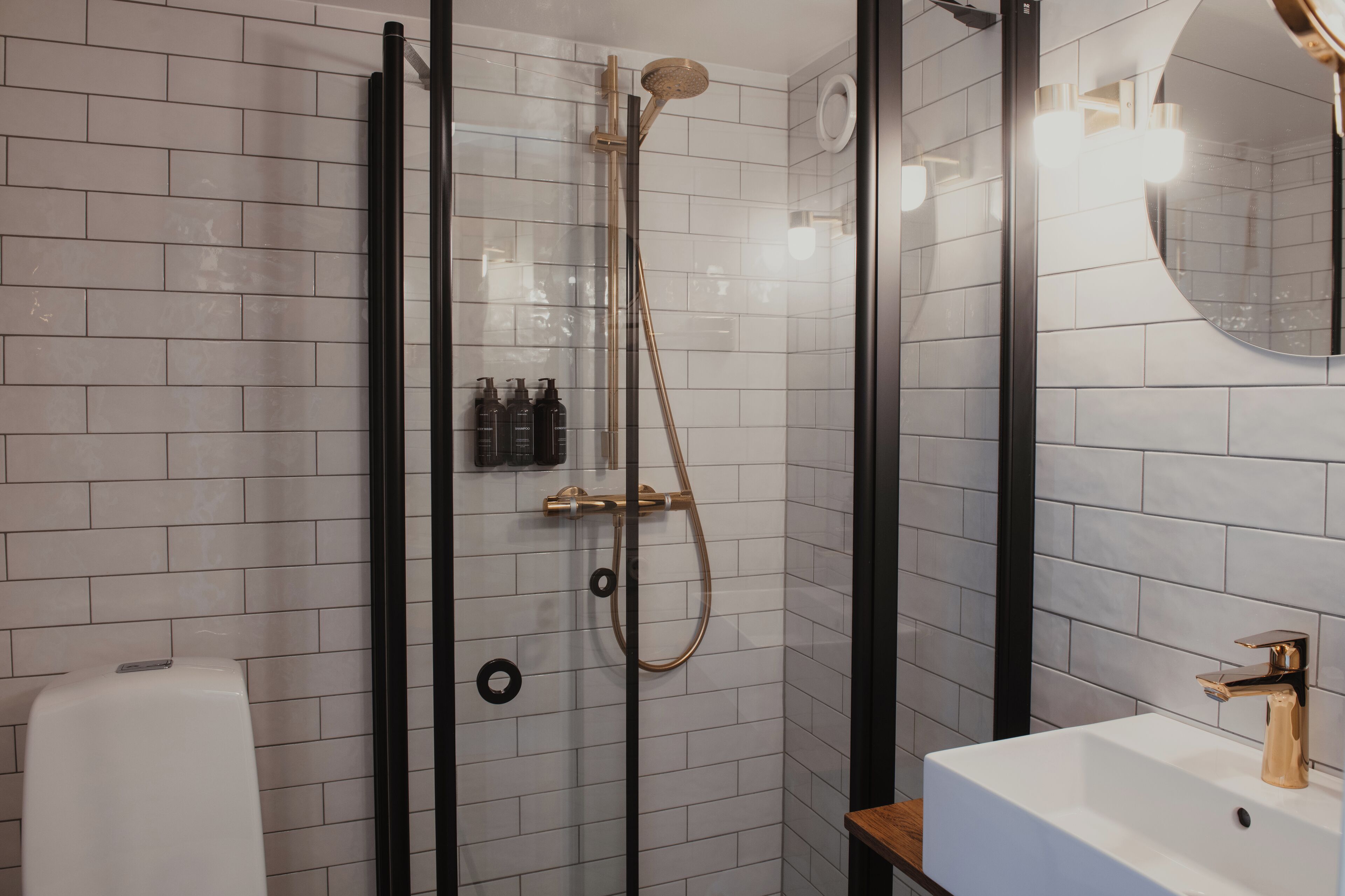 Une salle de bain moderne avec une douche à parois de verre, un lavabo blanc et un miroir.