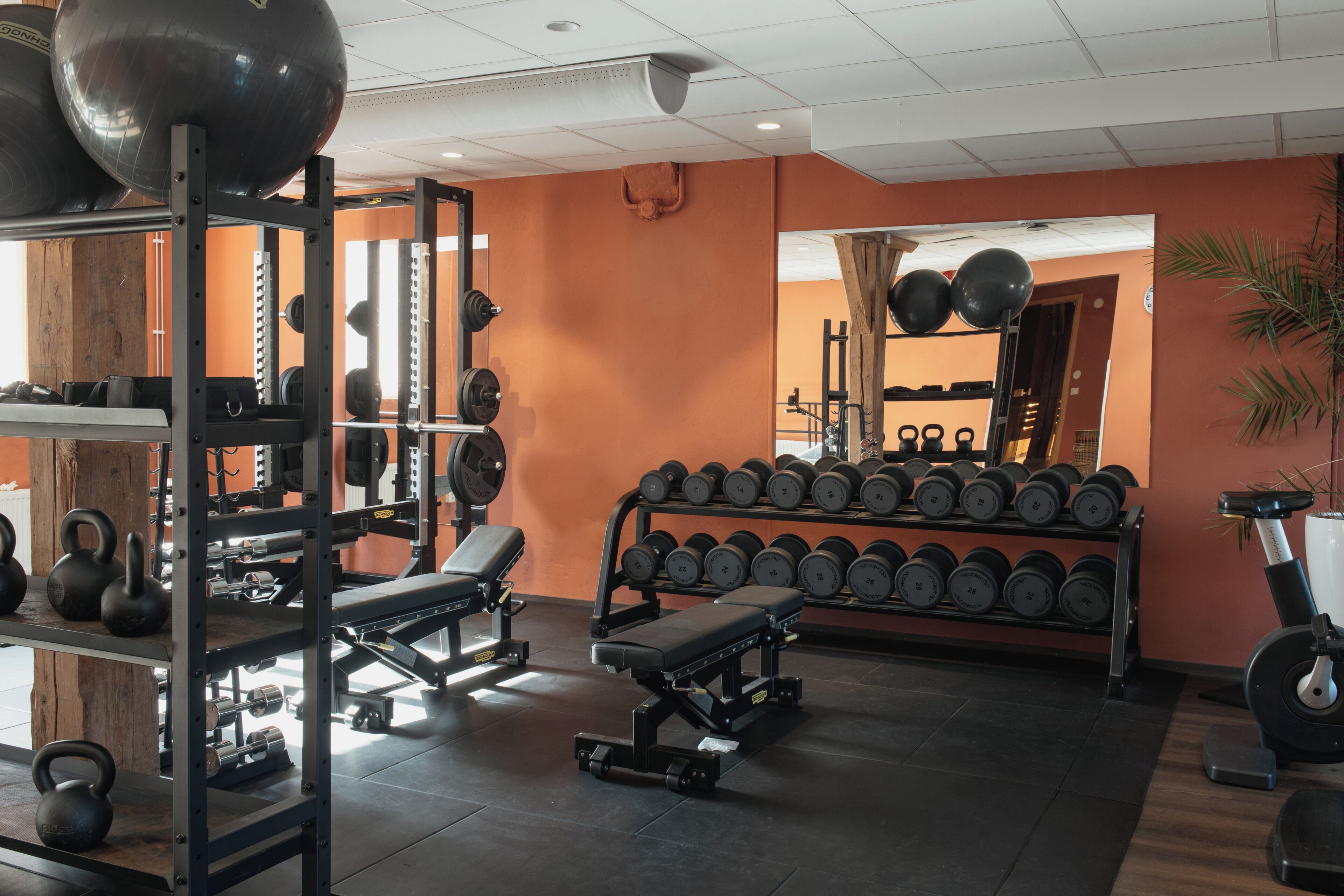 A gym with weightlifting equipment, dumbbells, kettlebells, and exercise machines.