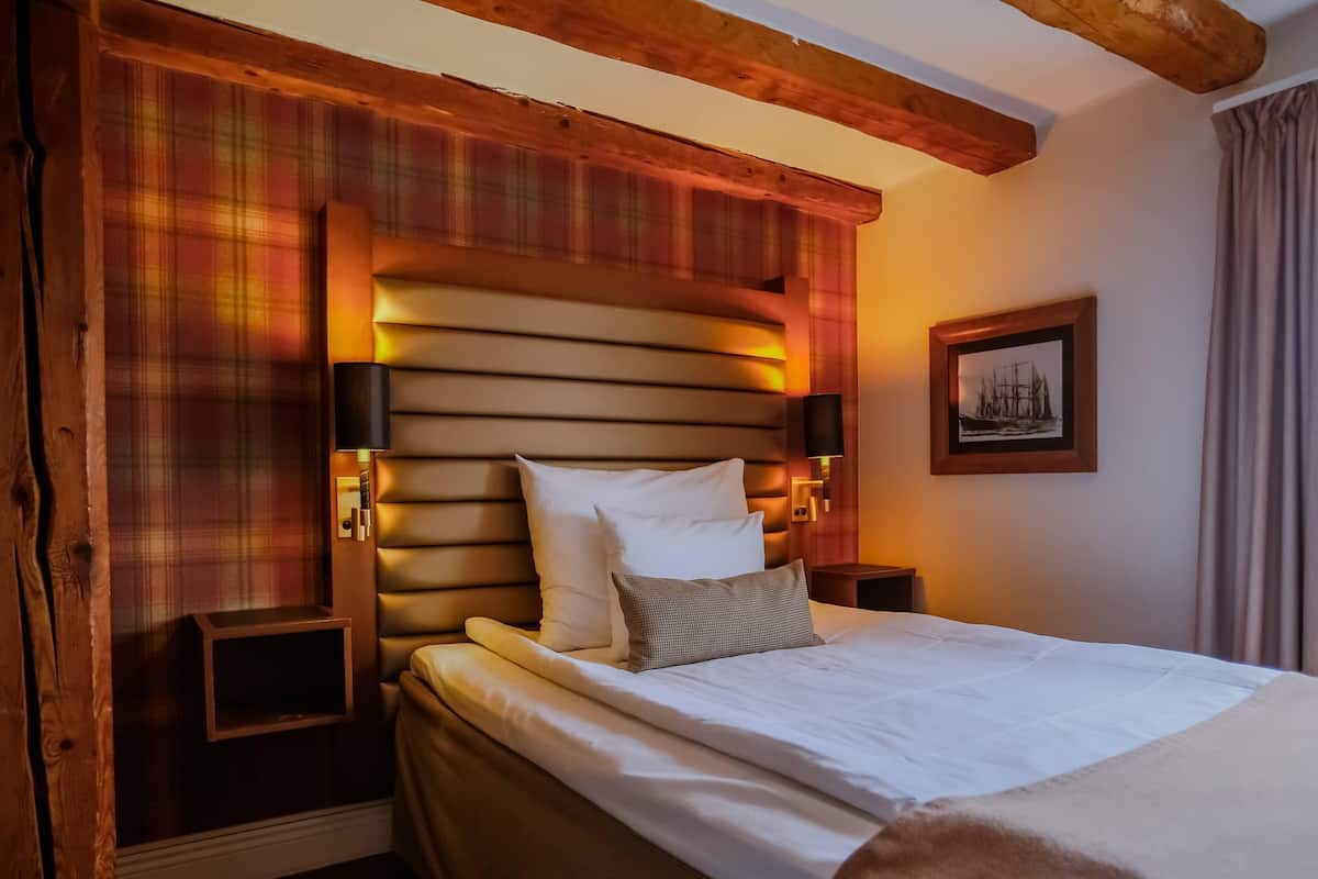 A neatly made bed with white and gray pillows, wooden headboard, and bedside lamps.