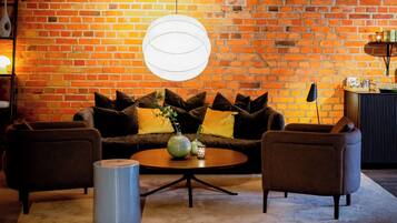A cozy living room with a brick wall, a round coffee table, and two armchairs.