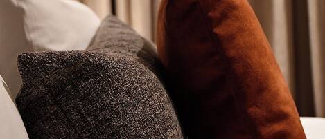 A bed with a white pillow, a grey textured pillow, and a brown pillow.