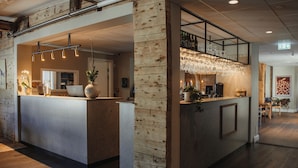 Un área de bar moderna con un revestimiento de madera, iluminación colgante y una vitrina de vidrio.