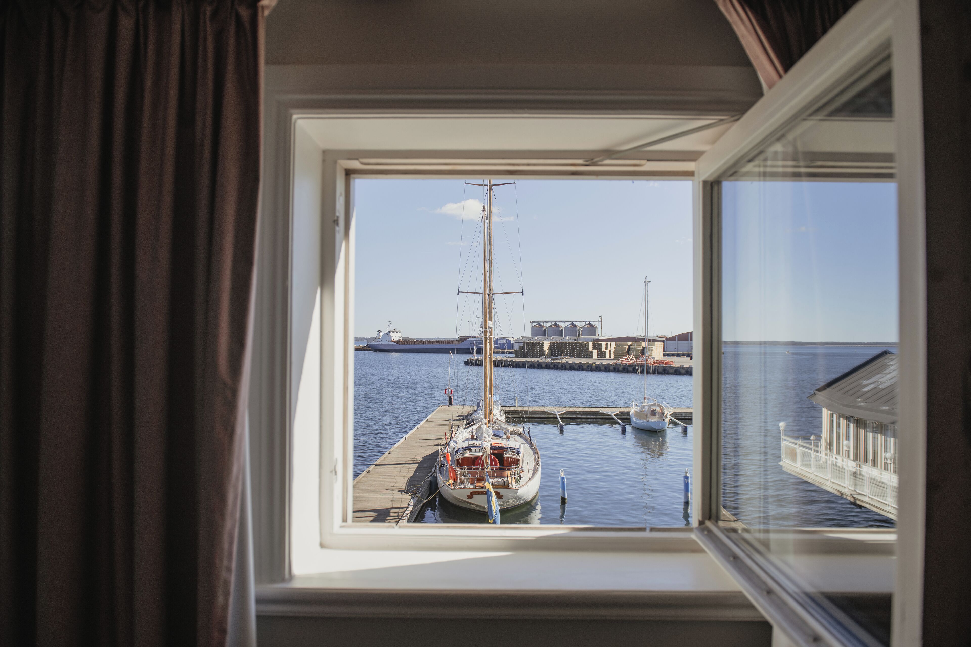 A view from a window of a docked sailboat at a marina.