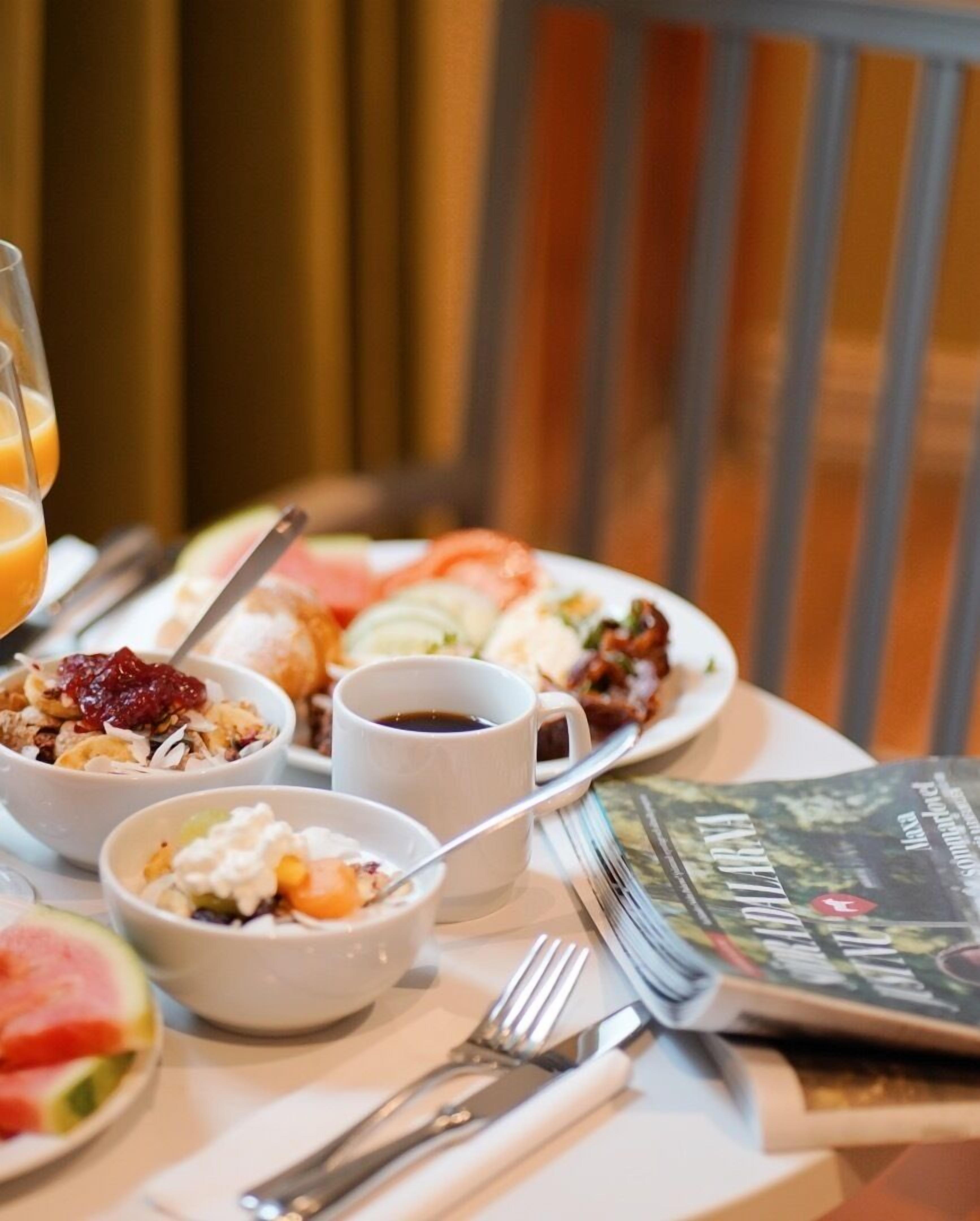 Une table de petit-déjeuner avec différents plats, une tasse de café et un magazine.