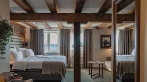 Habitación de hotel con dos camas, una mesita, una silla, una radio y vistas a la ciudad.