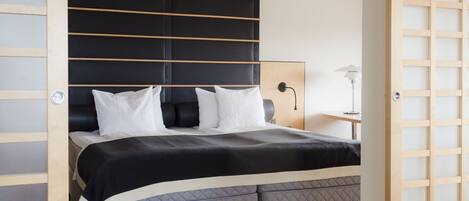 Un dormitorio moderno con una cama grande, una mesita de noche y una lámpara.