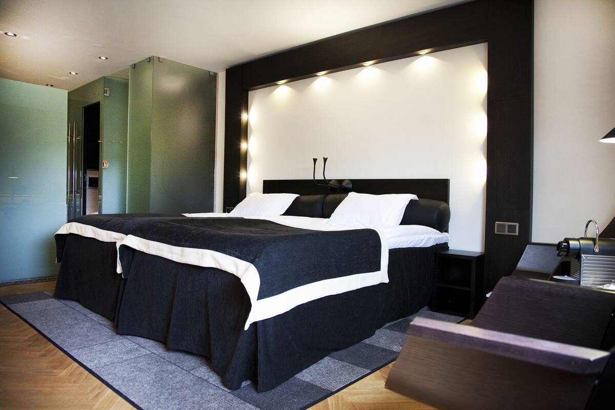A modern bedroom with a large bed, bedside tables, a desk, and a chair.