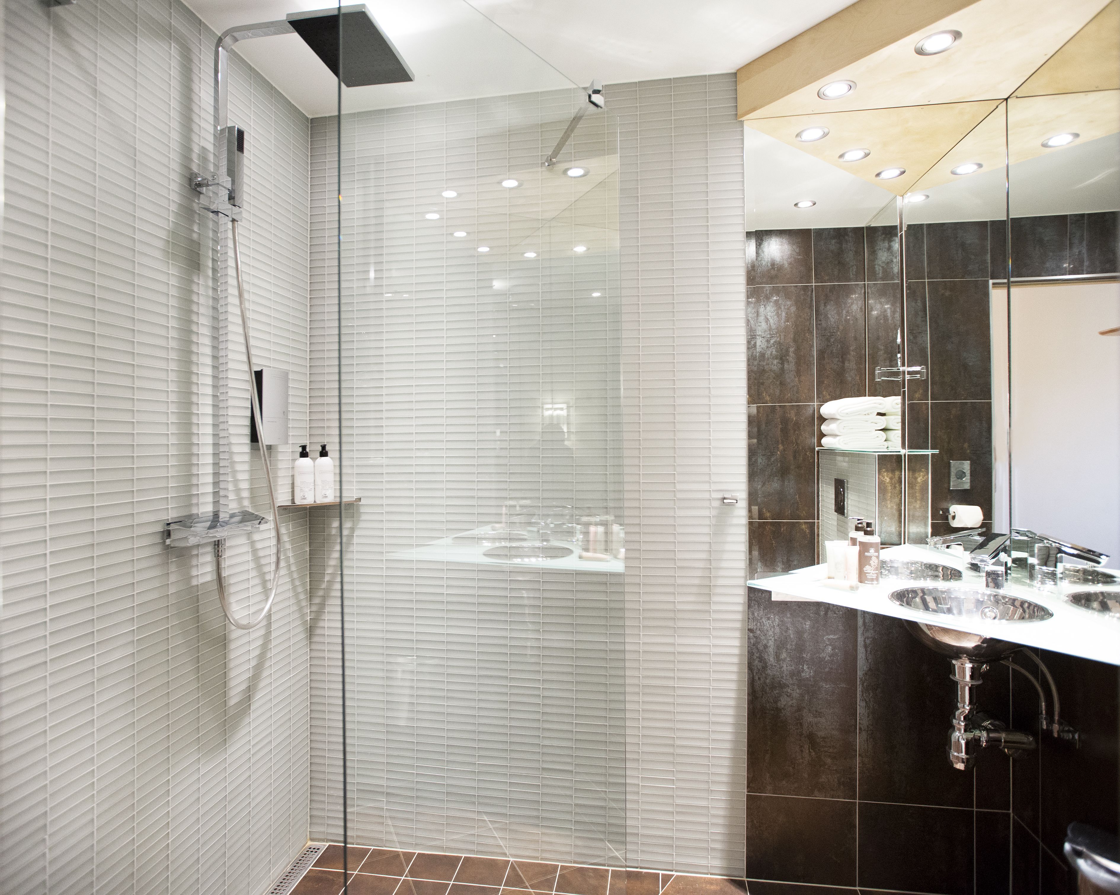 A modern bathroom with a glass-enclosed shower, a vanity with a mirror, and a sink.