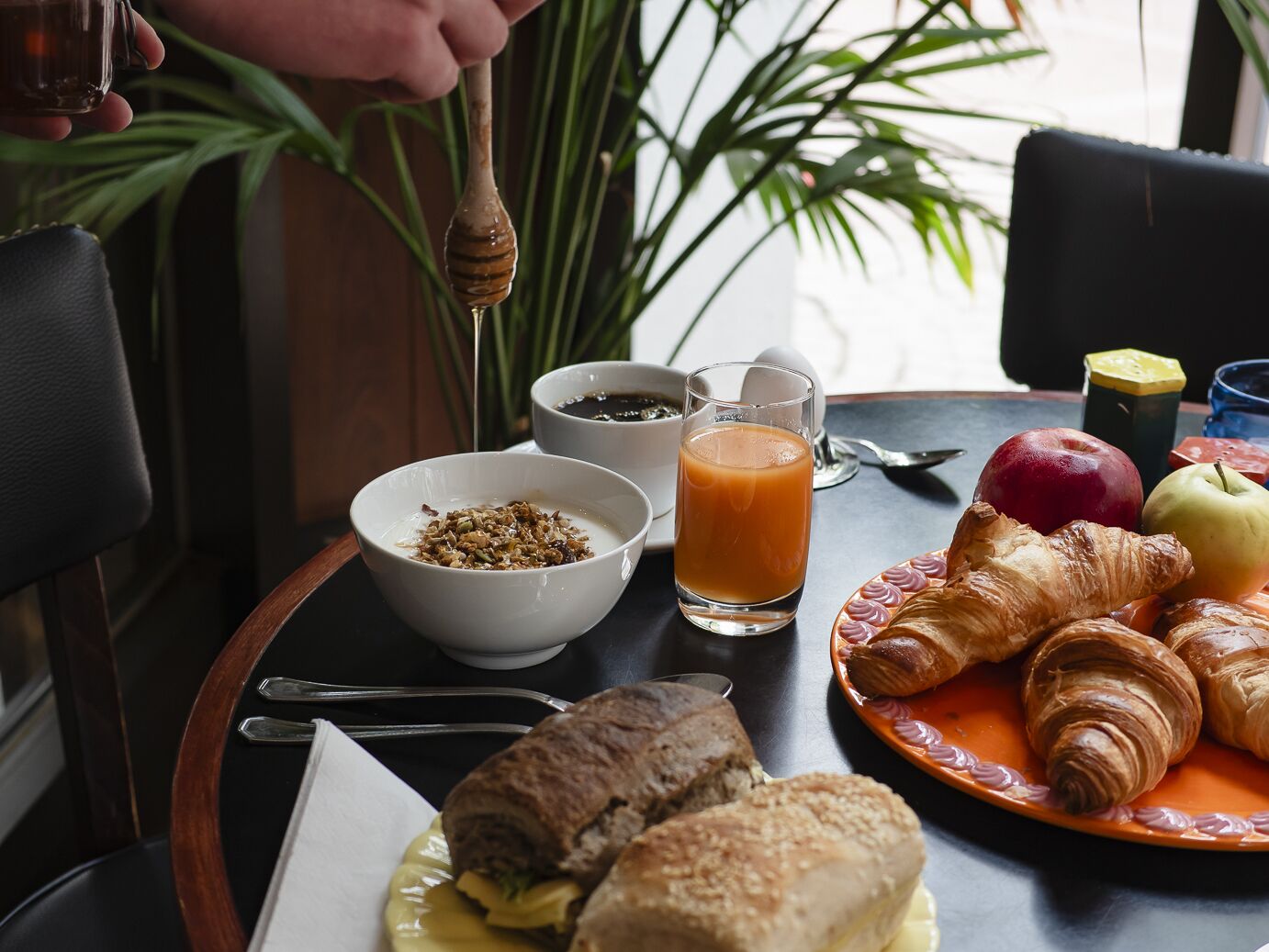 Disposição para o café da manhã com croissants, frutas, um copo de suco de laranja e uma tigela de cereal.