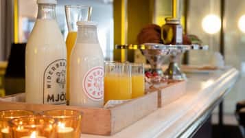 Una barra de desayuno con botellas de leche y jugo, una bandeja con vasos de jugo de naranja y velas.