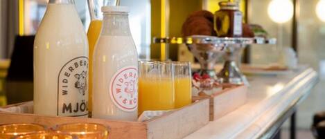 Una barra de desayuno con botellas de leche y jugo, una bandeja con vasos de jugo de naranja y velas.