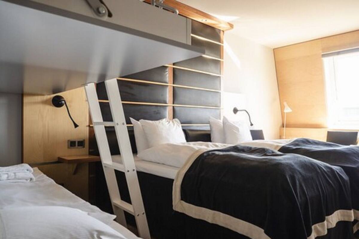 A bunk bed room with a ladder, a desk, and a lamp.
