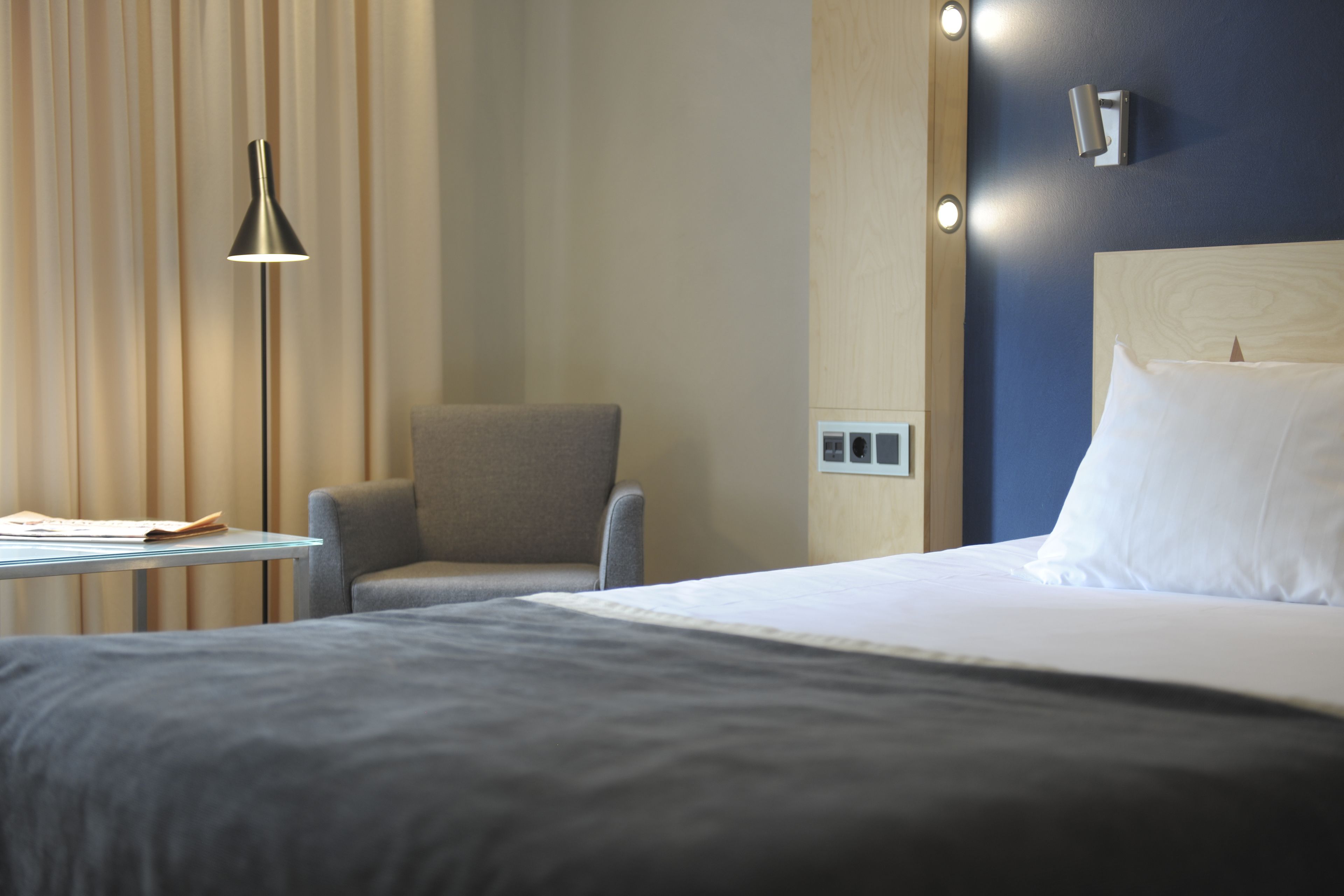Una habitación de hotel con cama, una silla, una mesa y una lámpara.