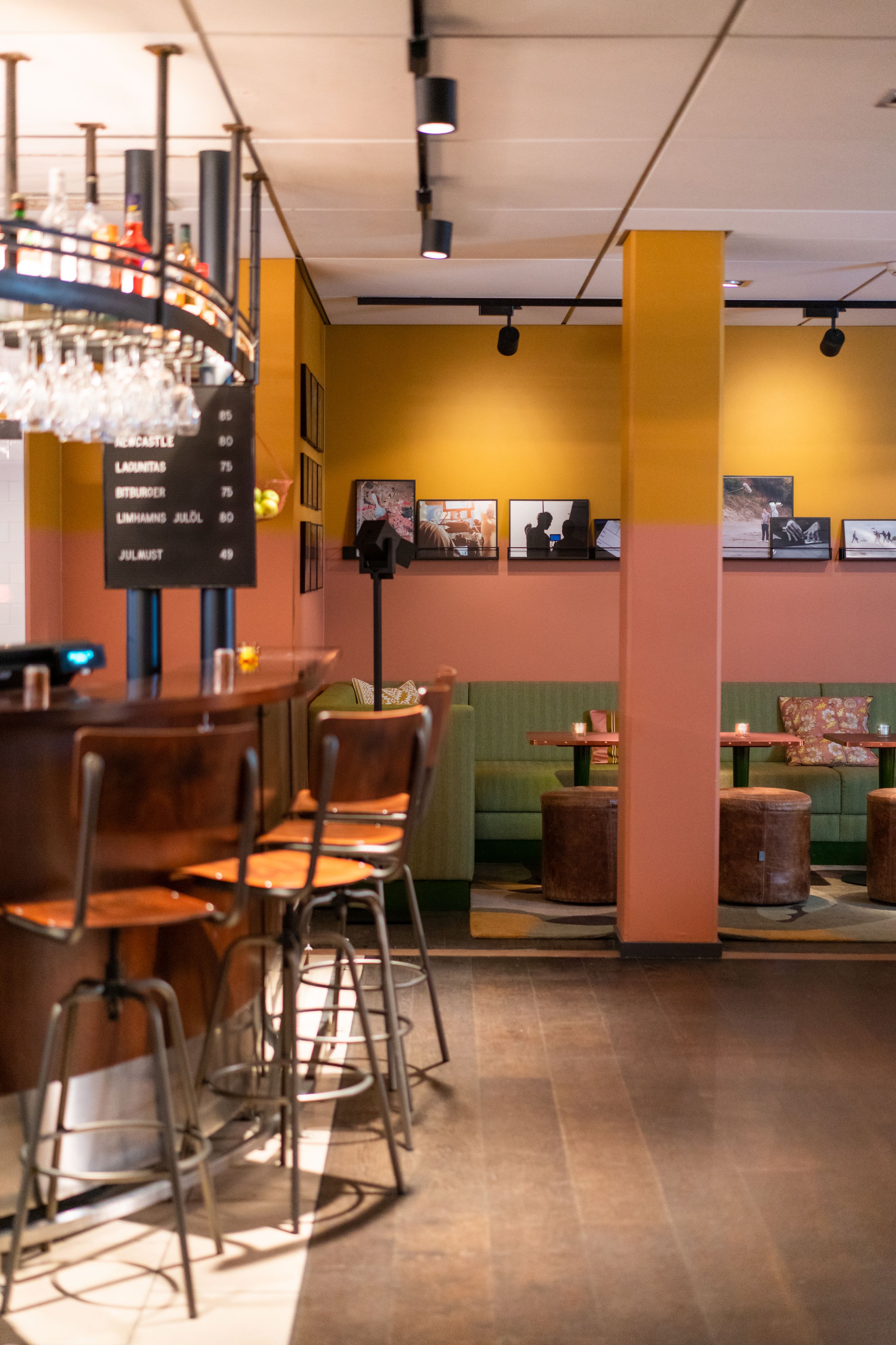 A restaurant interior with a bar area, wooden chairs, and a green cushioned seating area.