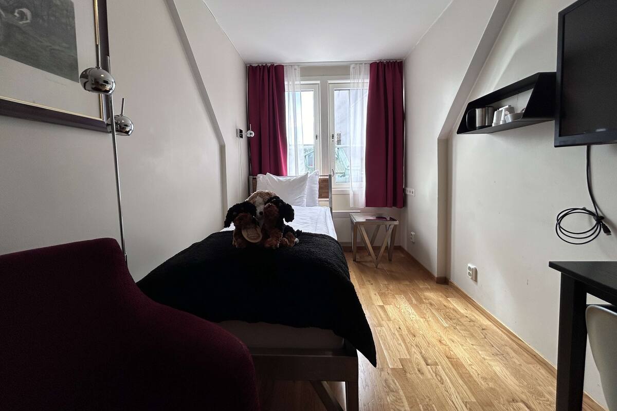 A small, cozy room with a bed, a desk, and a TV.