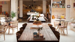 A spacious dining area with a long wooden table, wicker chairs, and a central island with a small table and chairs. - Best Western Plus Hotel Noble House (Malmö)