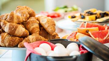 Un buffet de petit-déjeuner avec des croissants, des pamplemousses et des œufs.