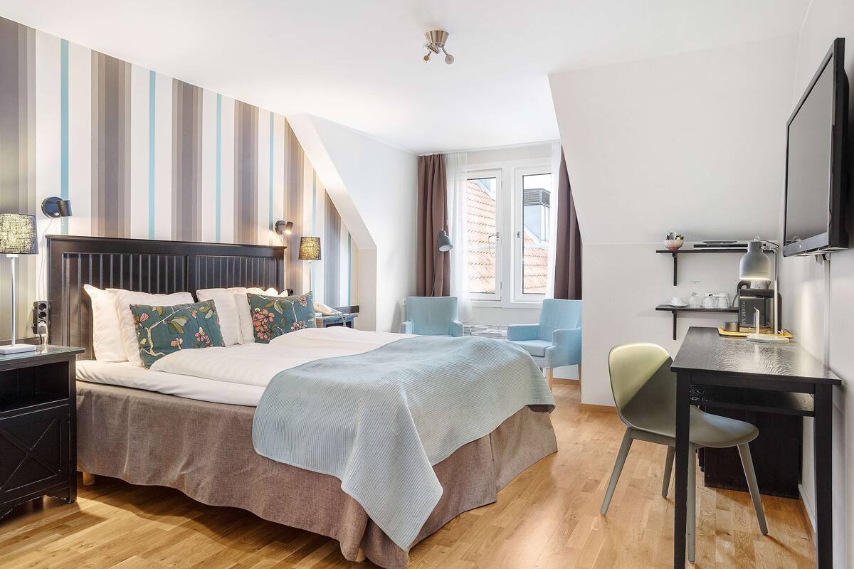 A modern bedroom with a bed, bedside tables, a desk, and a chair.