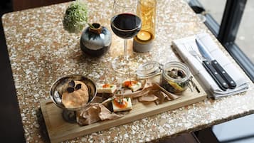 A table with a variety of food items, a glass of red wine, a candle, and a vase with a plant.