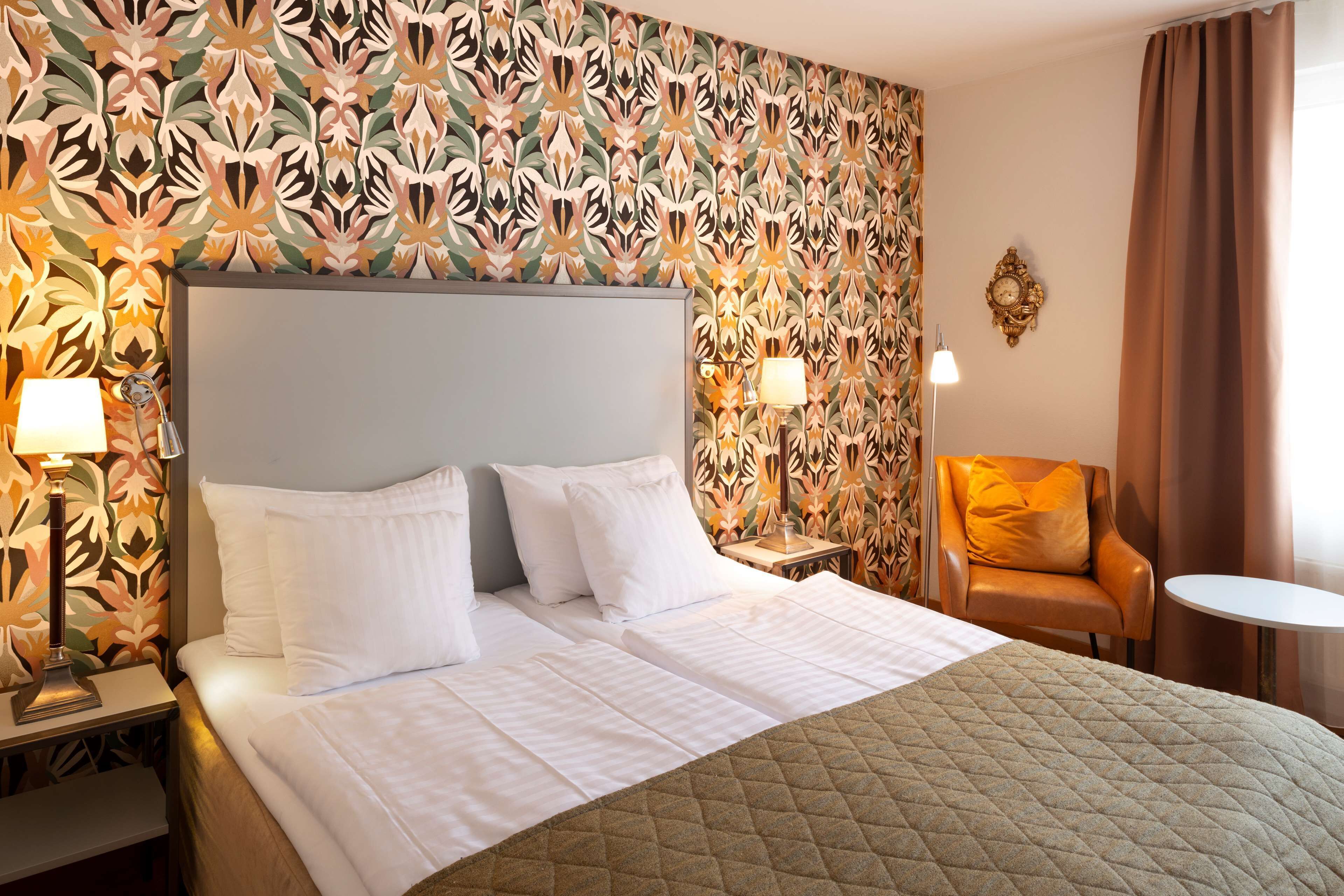 A hotel room with a large bed, two bedside tables with lamps, a chair, and a small table.