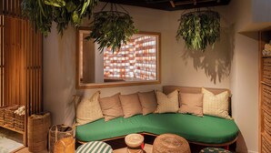 A cozy room with a curved sofa, several cushions, wicker baskets, and hanging plants. - Best Western Plus Hotel Noble House (Malmö)