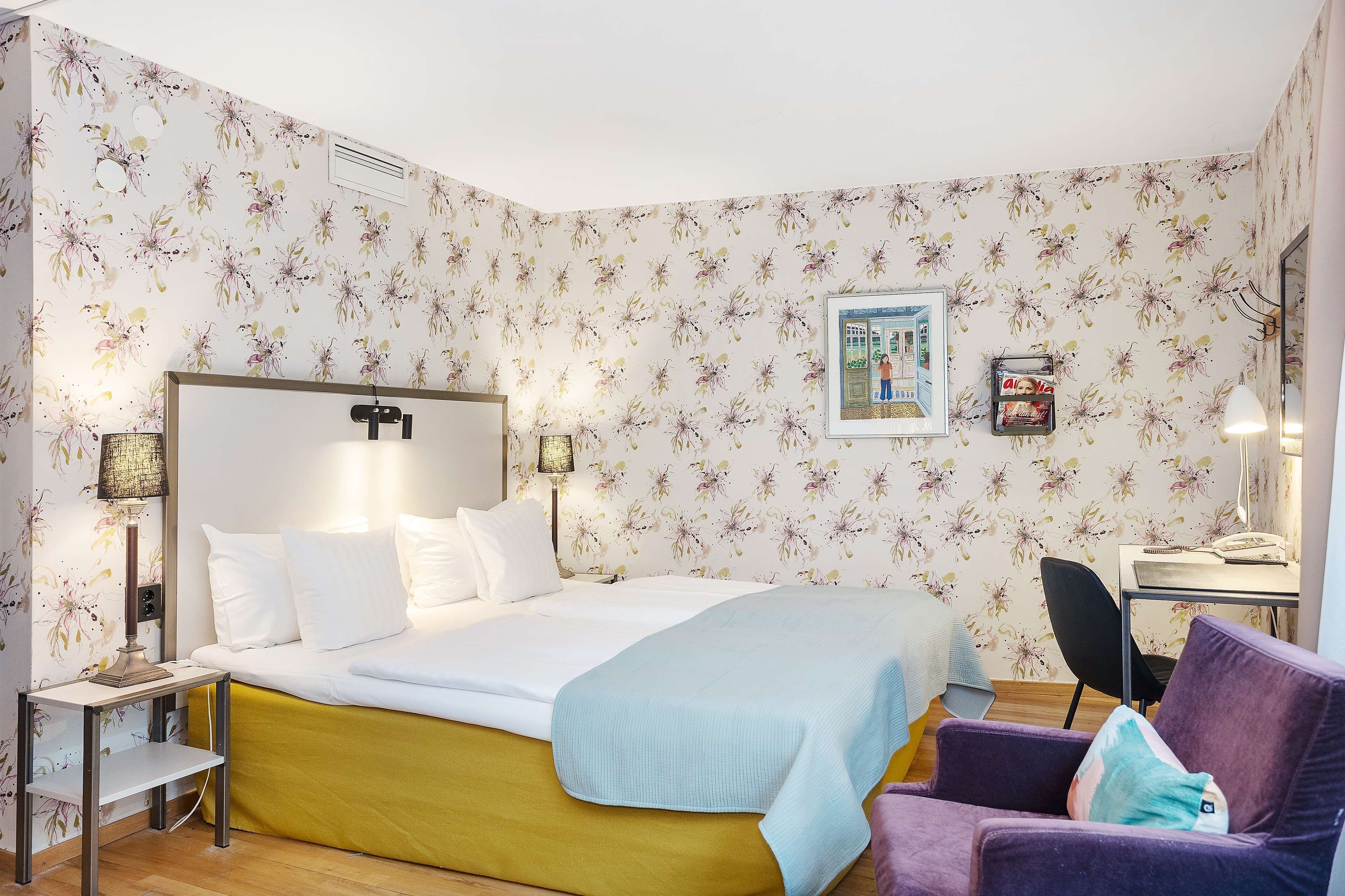 Ein Hotelzimmer mit einem Bett, einem Schreibtisch, einem Stuhl und einem kleinen Tisch.