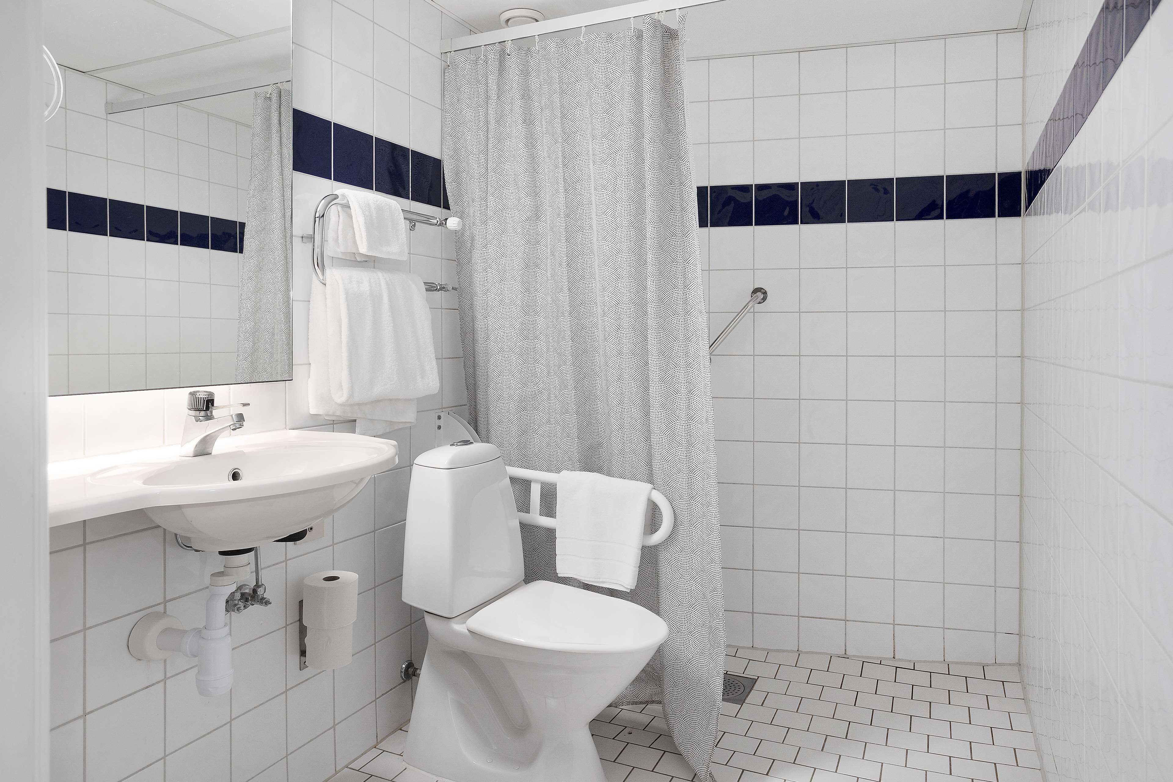 Une salle de bain avec un lavabo blanc, des toilettes et un rideau de douche.