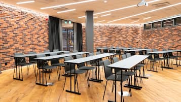 Un salón de conferencias con paredes de ladrillo, piso de madera y mobiliario negro moderno.