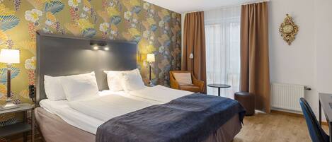 Una habitación de hotel con una cama grande, una silla, un escritorio y un reloj de pared.
