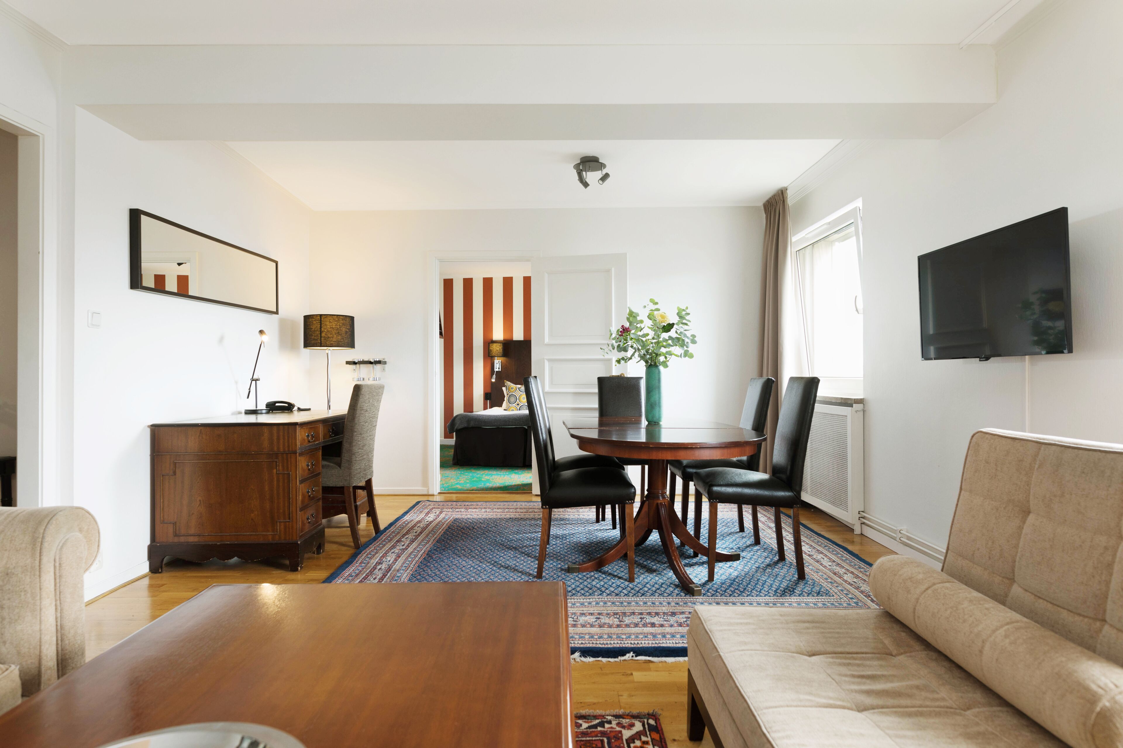 Una sala de estar con una mesa de centro de madera, un sofá color beige y un comedor con una mesa redonda y sillas.