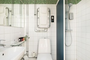 Un bany modern amb una prestatgeria de vidre plena de productes de tocador, un vàter blanc, un lavabo de vidre i una zona de banyera.