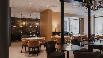 A modern dining area with round tables and chairs, pendant lighting, and a fireplace.