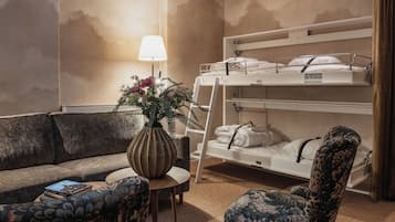 Una habitación de hotel con literas, un sofá, una mesita y una lámpara.
