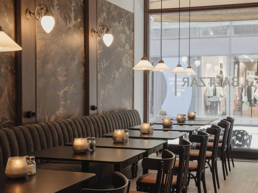 A restaurant with a long counter, multiple tables, and a large window.
