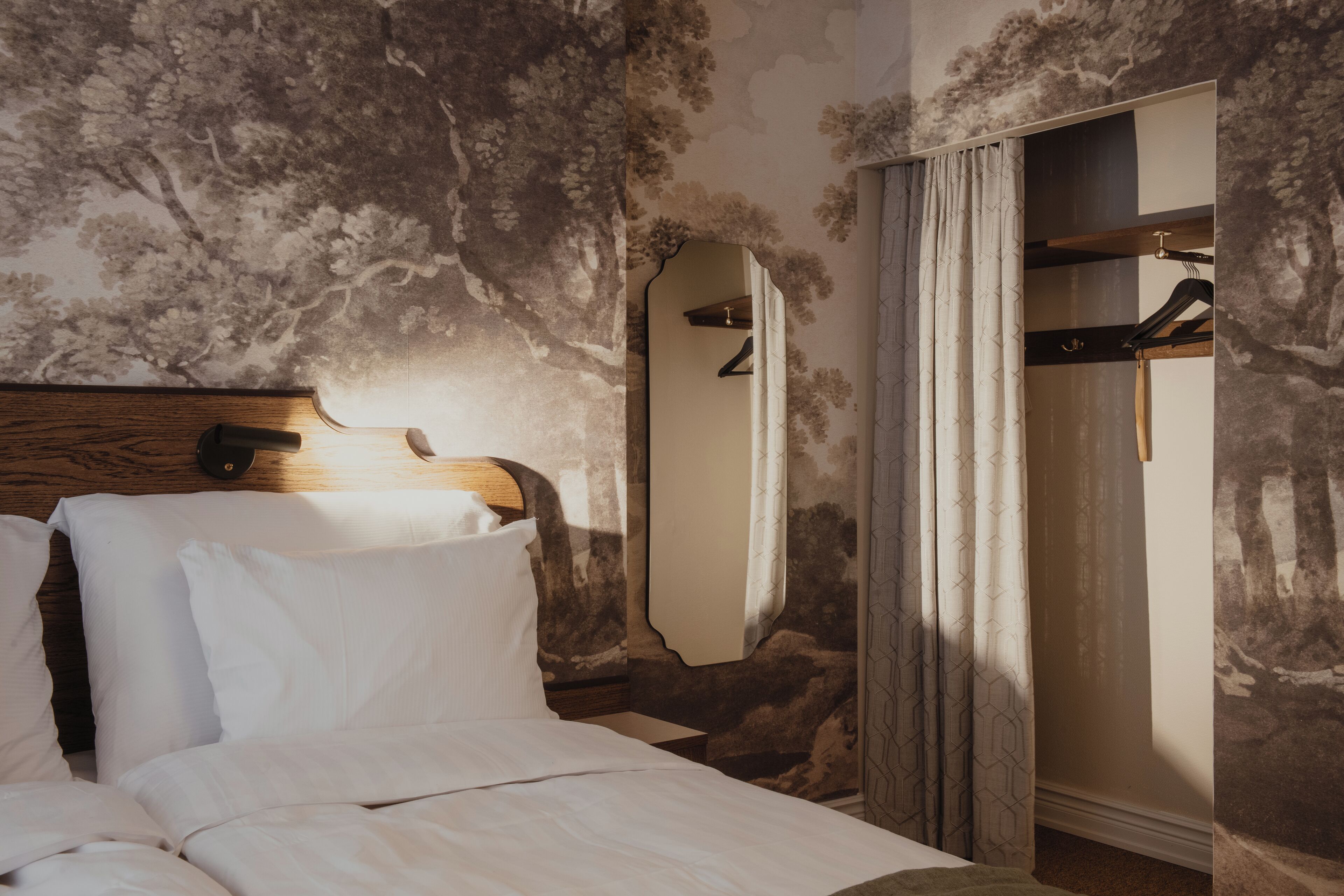 Una habitación de hotel con cama, cabecero de madera, espejo y armario.