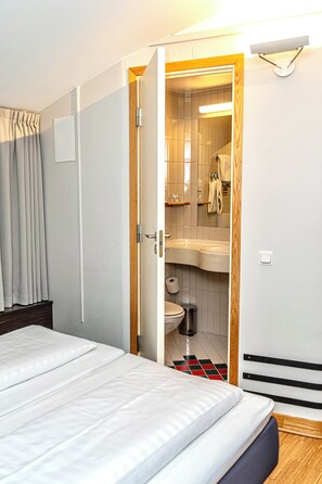 A hotel room with a bed, a bathroom with a sink and toilet, and a wooden door. - Comfort Hotel Malmö (Malmö)