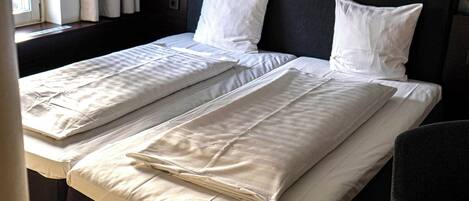 A hotel room with a large bed, a headboard with a microphone design, and a window with curtains.