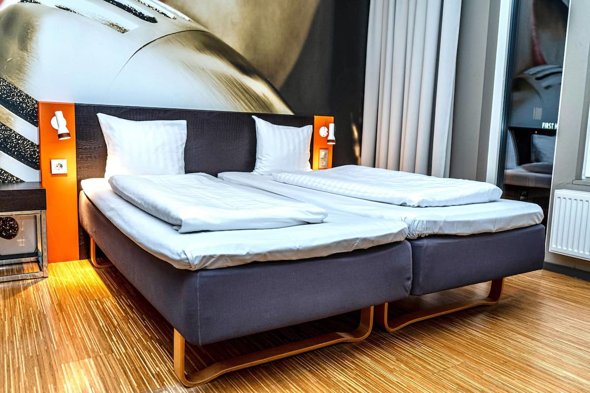 Una cama doble con cabecera oscura y dos mesitas de noche, cada una con una lámpara.