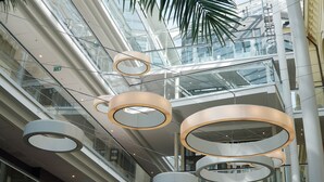Een modern interieur met meerdere niveaus, glazen balustrades en ronde plafondlampen.