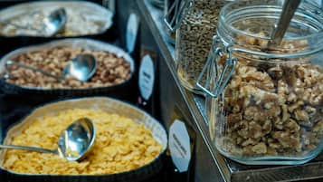Un bufé con diversos alimentos en recipientes de vidrio, cada uno con una cuchara.