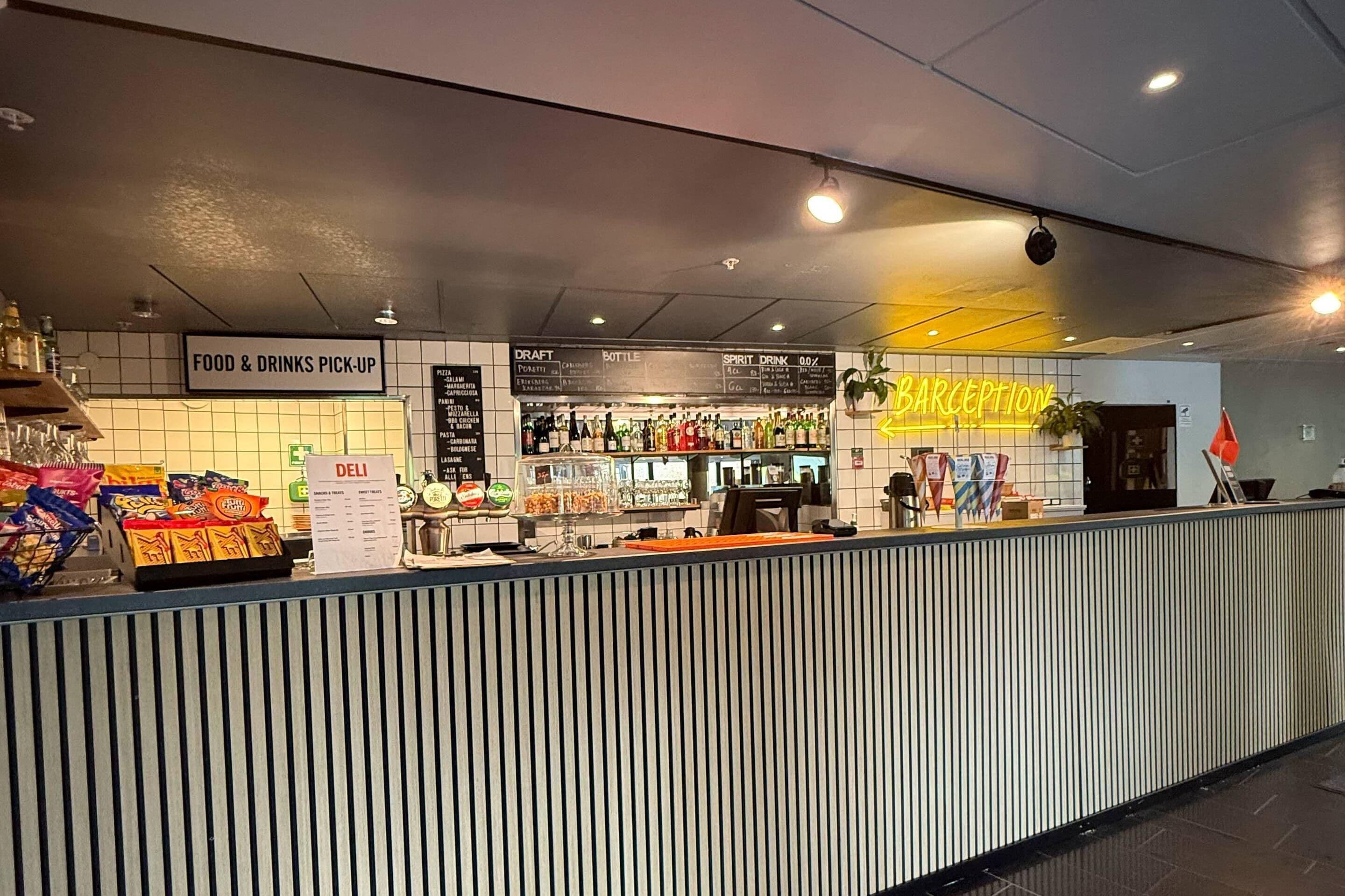 En skranke til afhentning af mad og drikkevarer, med et deli-område, fadølsanlæg og bar.