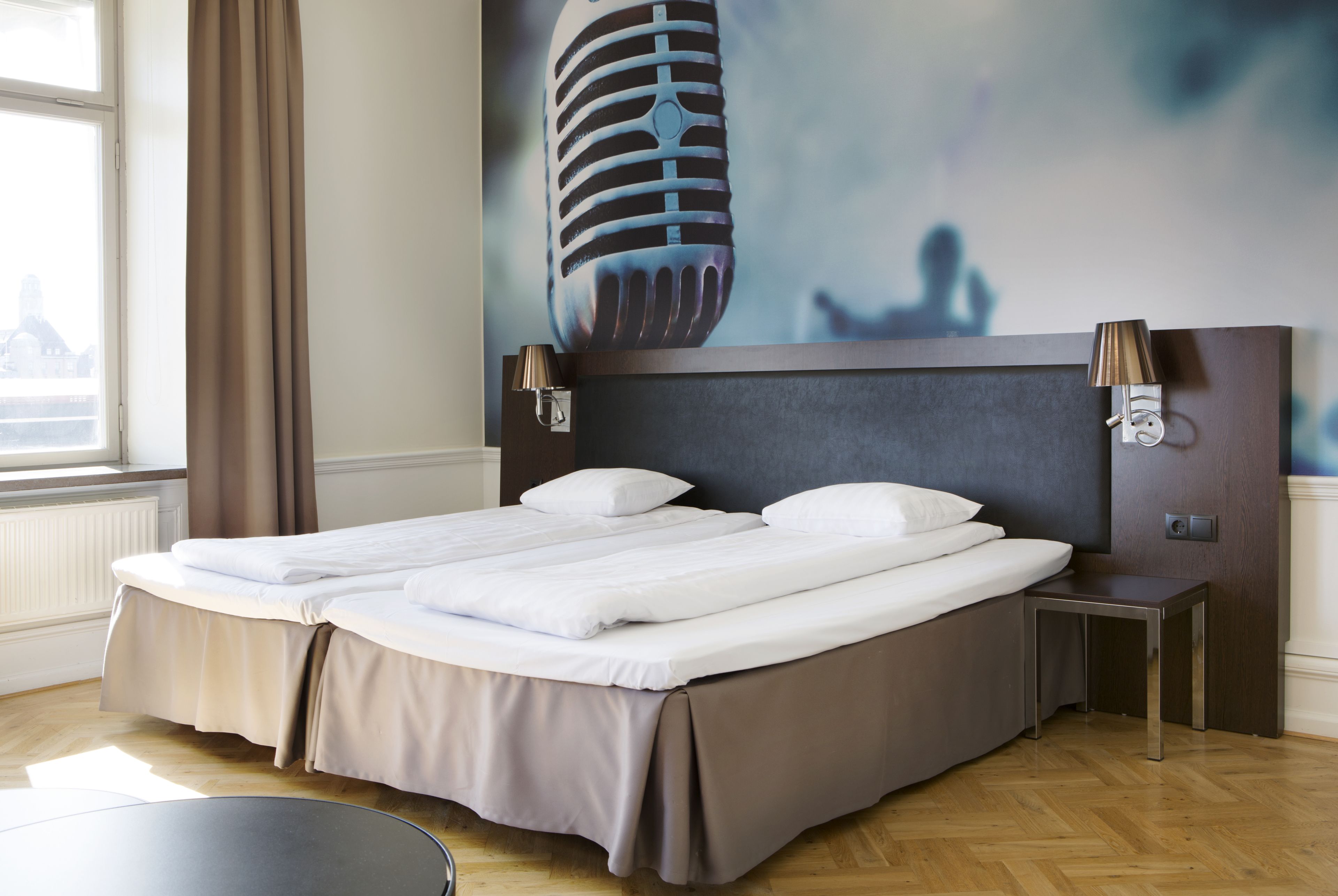 Cama doble con cabecera, mesitas de noche y vistas al exterior.
