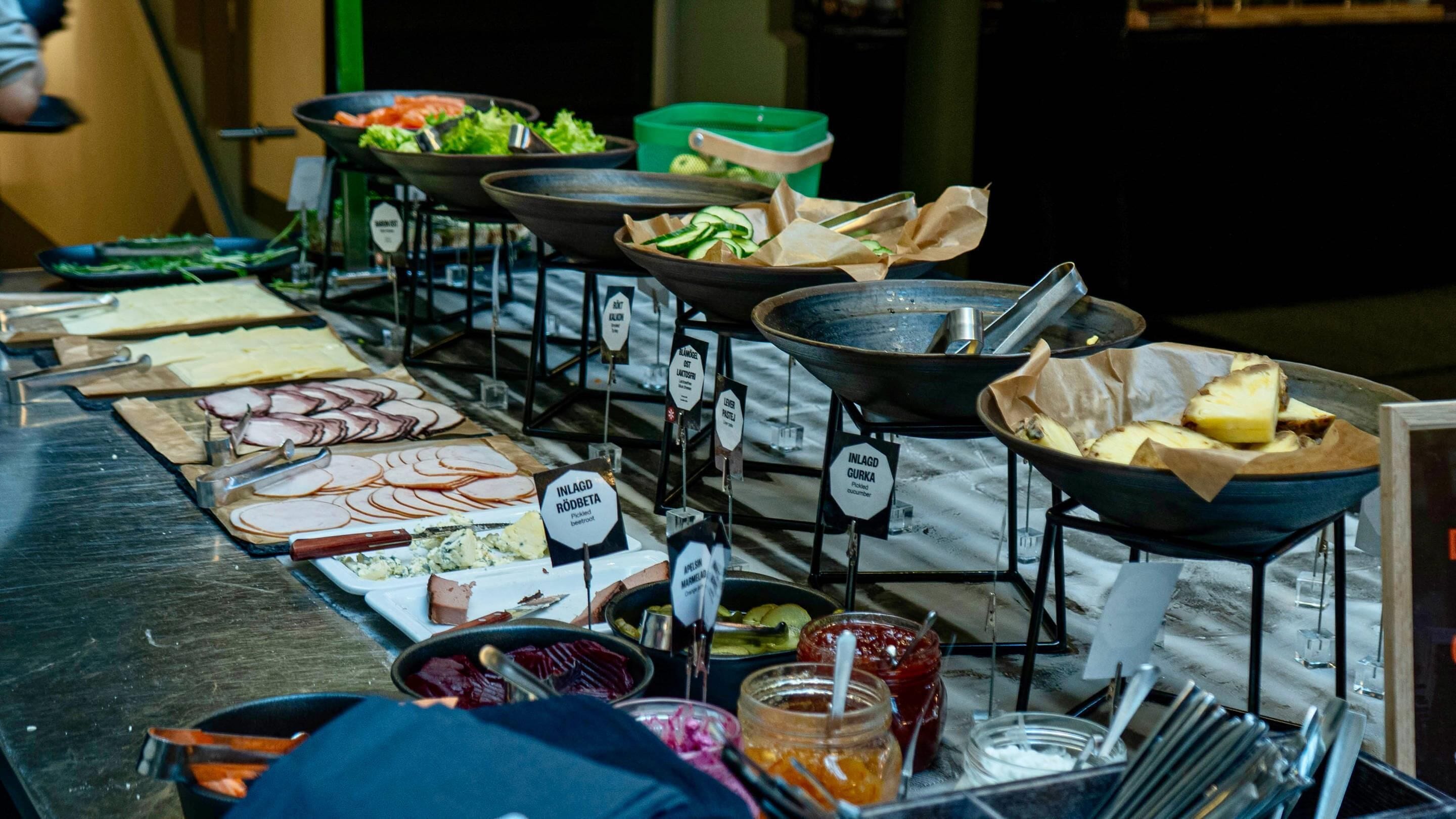 A buffet with various food options, including sliced meats, vegetables, and desserts.