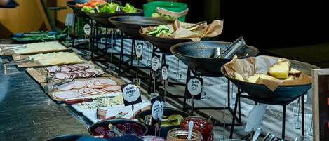 Un bufé con diversas opciones de comida, como carnes cortadas, verduras y postres.